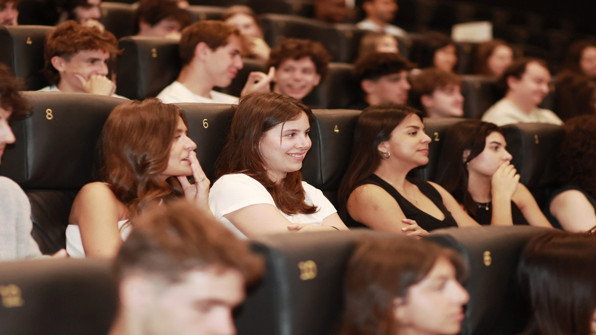 Auditorium rempli de jeunes spectateurs assis sur sièges numérotés pendant une projection.