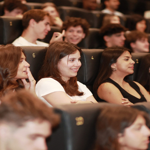 Auditorium rempli de jeunes spectateurs assis sur sièges numérotés pendant une projection.