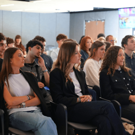 Audience attentive lors dune conférence professionnelle en salle moderne.