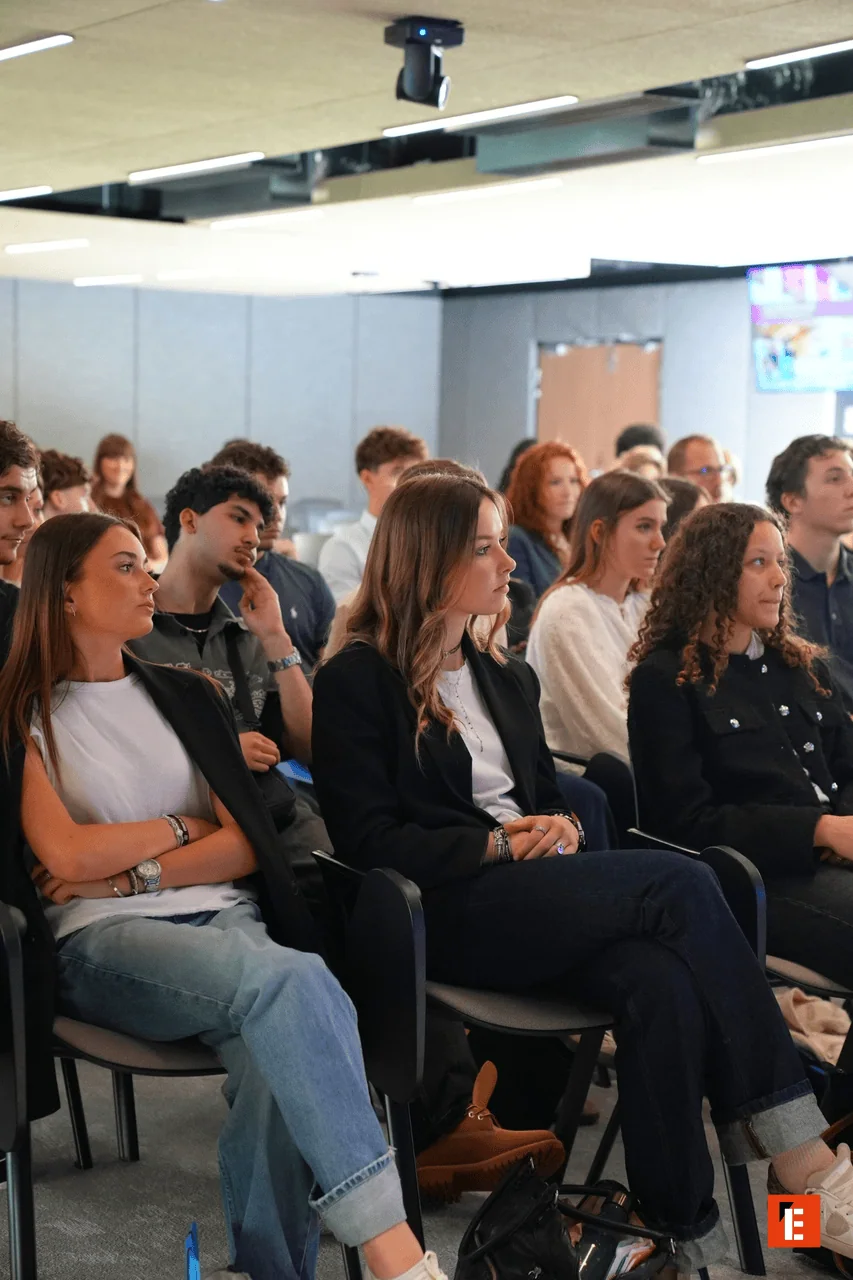 Audience attentive lors dune conférence professionnelle en salle moderne.