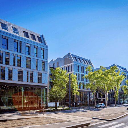 Bâtiments urbains modernes le long dune avenue avec tramway, façades vitrées et piétons.