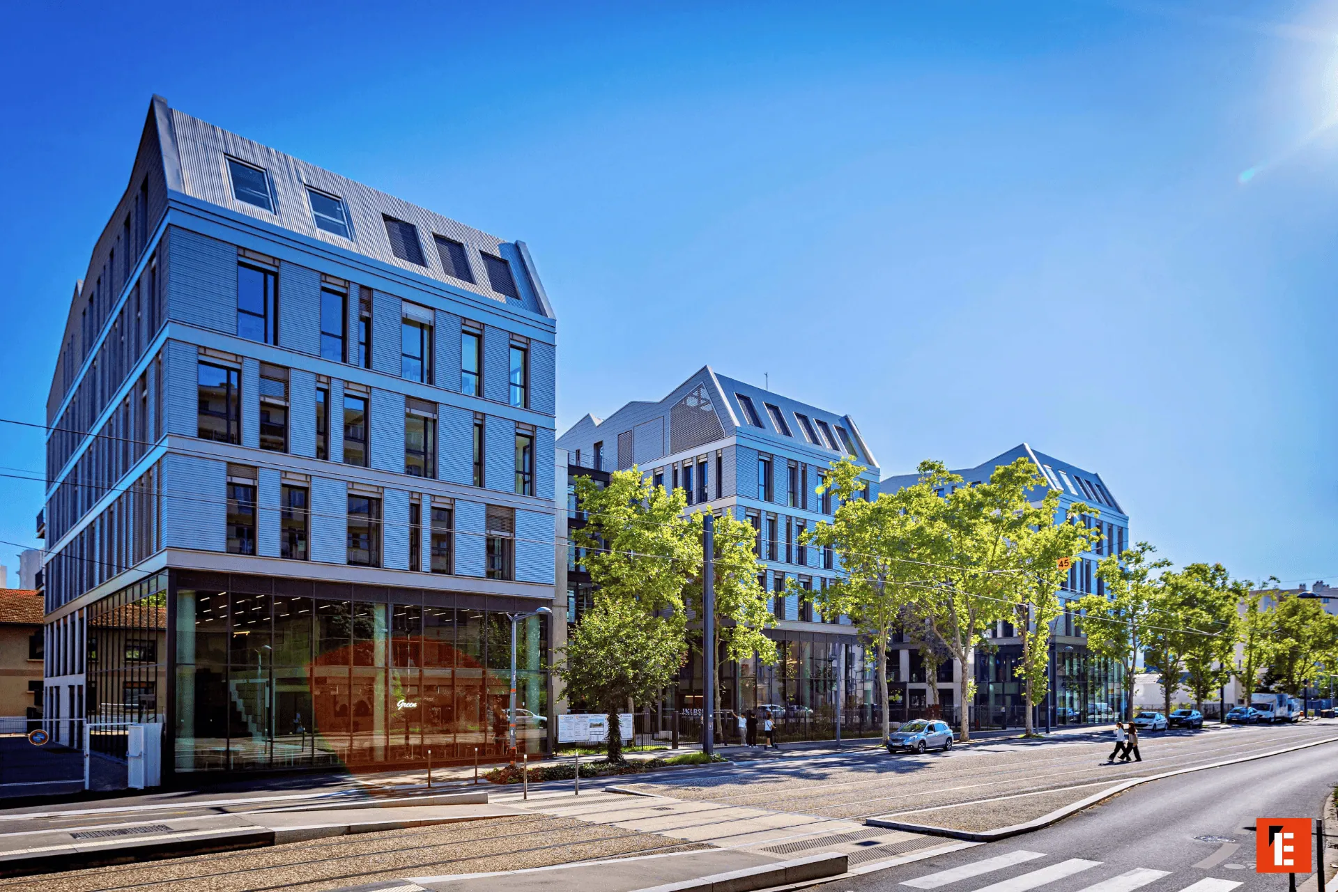 Bâtiments urbains modernes le long dune avenue avec tramway, façades vitrées et piétons.