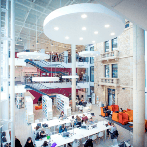 Bibliothèque moderne en atrium lumineux avec étages, escaliers, espaces détude et étudiants.