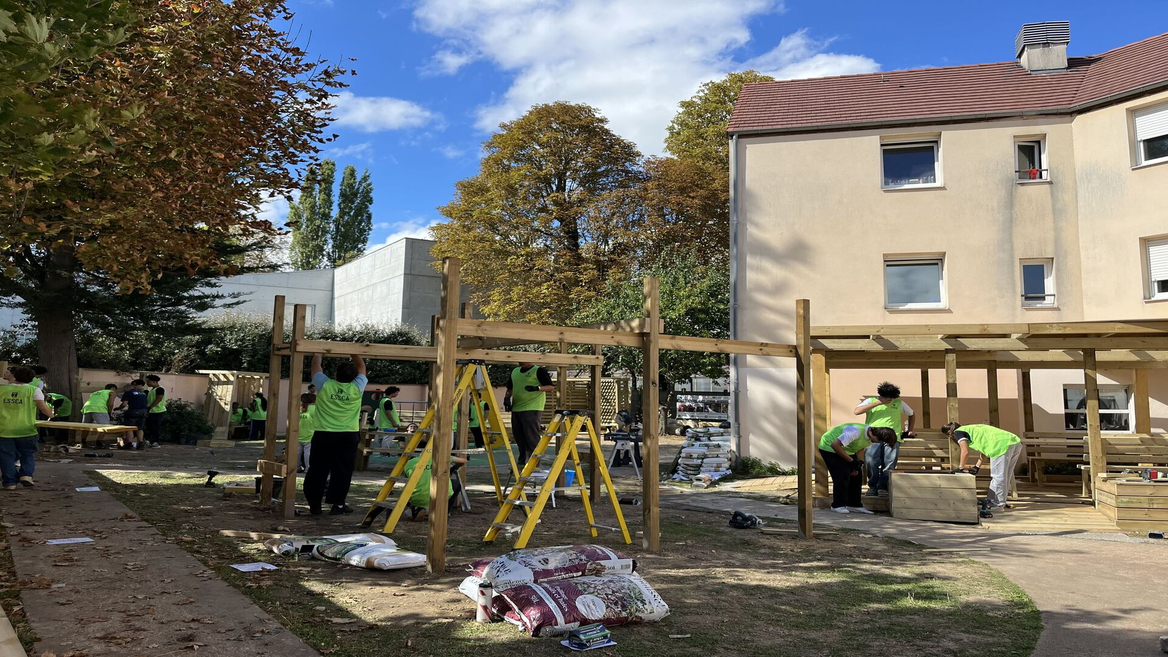 Bénévoles construisent une pergola en bois dans une cour urbaine en automne.