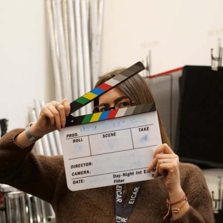 Portrait studio : clap de tournage masque le visage, seuls yeux et lunettes visibles.