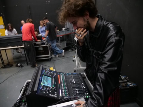 Ingénieur du son ajustant une console de mixage numérique en studio de répétition.