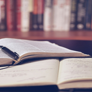 Carnet et stylo sur livre ouvert, table détude près dune bibliothèque.