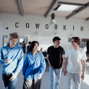 Espace coworking lumineux avec jeunes professionnels marchant et travaillant en espace ouvert.