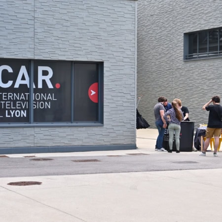 Façade EICAR Lyon, école de cinéma et télévision, groupe détudiants près dun stand.
