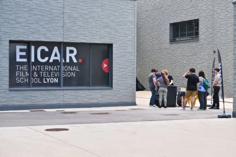 Façade EICAR Lyon, école de cinéma et télévision, groupe détudiants près dun stand.
