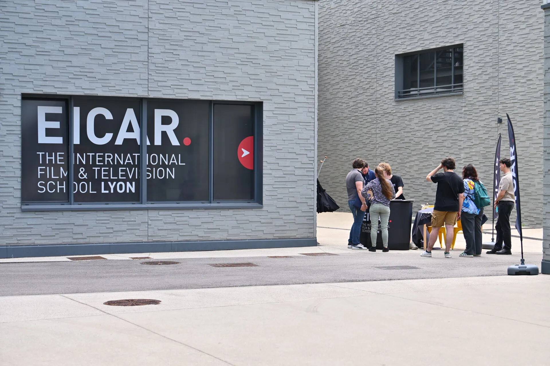 Façade EICAR Lyon, école de cinéma et télévision, groupe détudiants près dun stand.