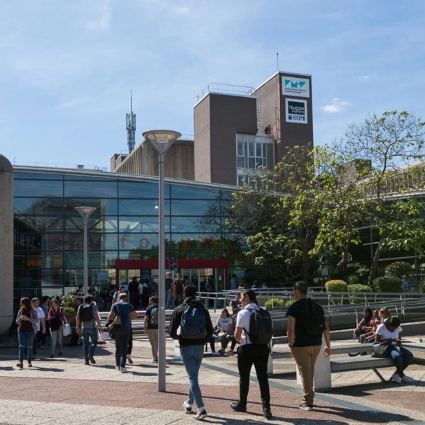Place devant IMT-BS : étudiants sur le campus, façade vitrée et volumes en béton.