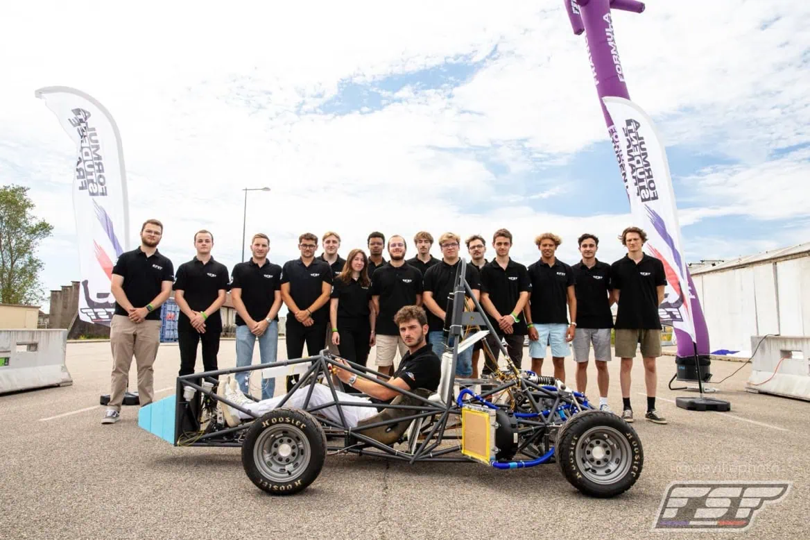 Équipe étudiante présentant voiture prototype monoplace de course légère.