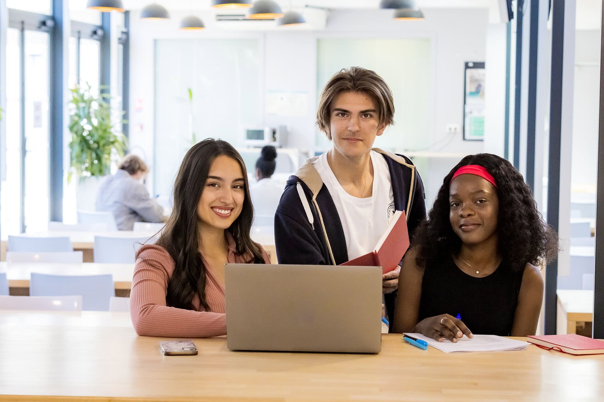 Étudiants en collaboration sur ordinateur portable dans espace détude lumineux et moderne.