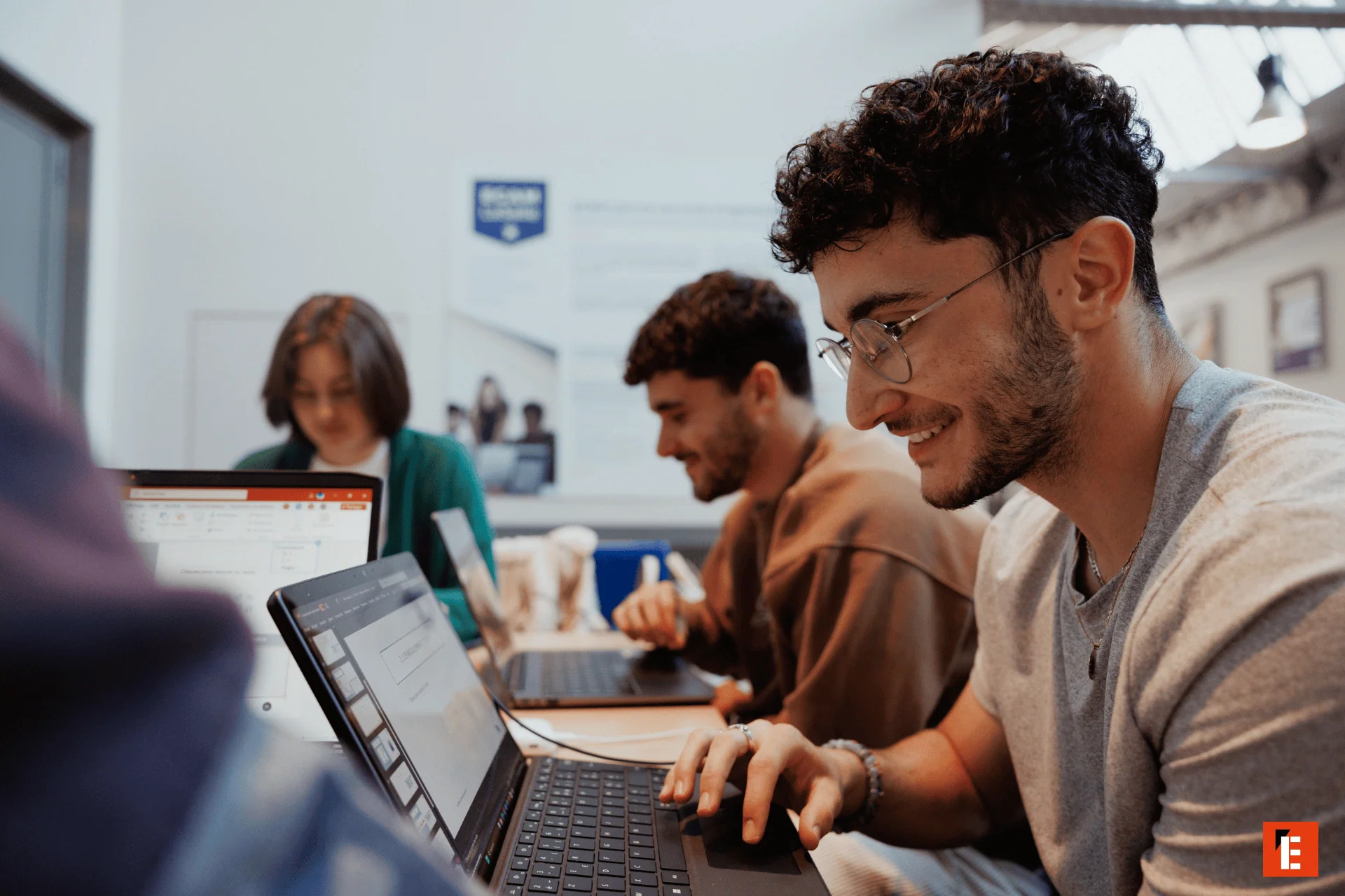 Étudiants travaillant en groupe sur ordinateurs portables dans un espace détude lumineux.