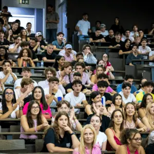 Auditoire étudiants bondé en amphithéâtre lors dune conférence, foule attentive et décontractée.