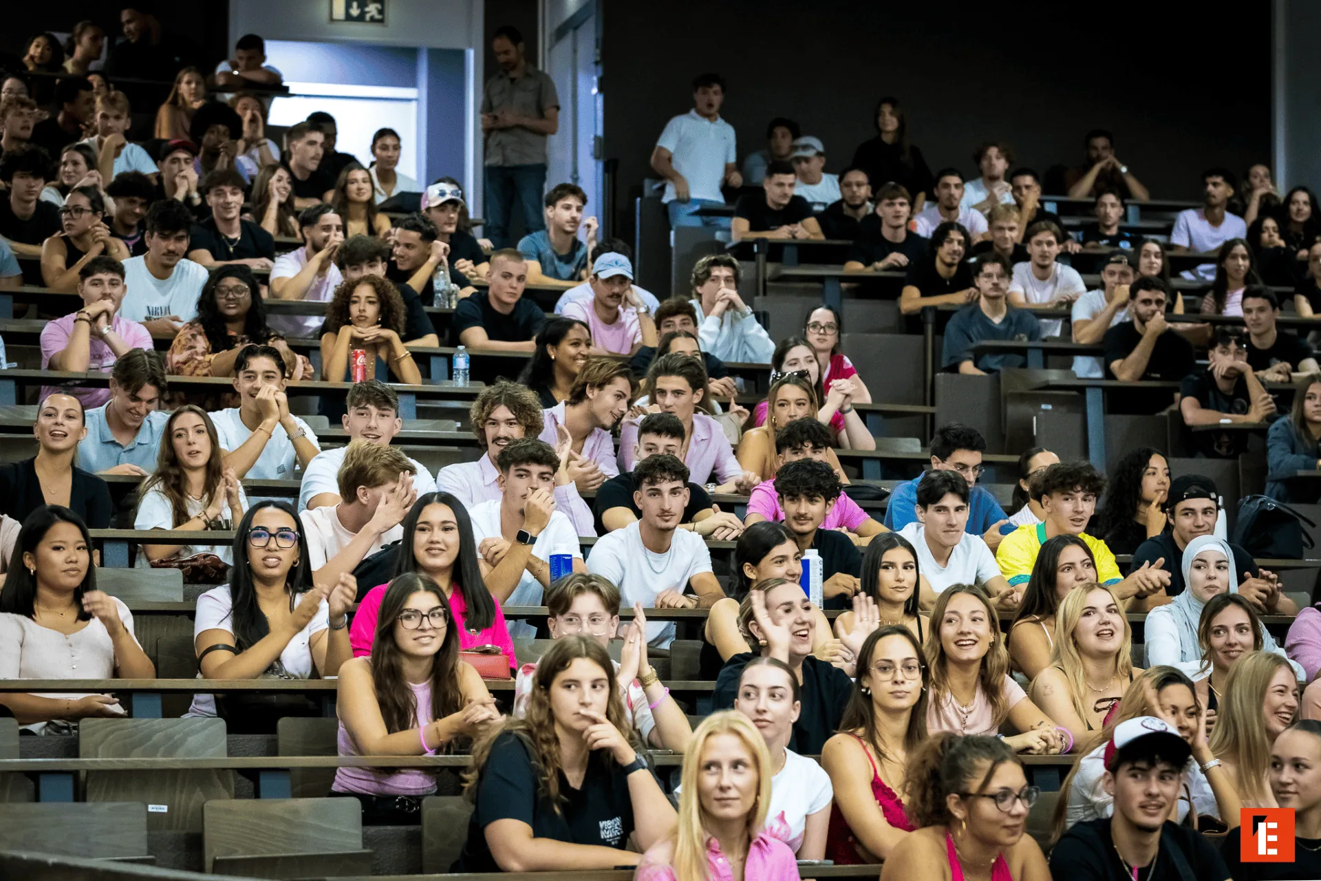 Auditoire étudiants bondé en amphithéâtre lors dune conférence, foule attentive et décontractée.