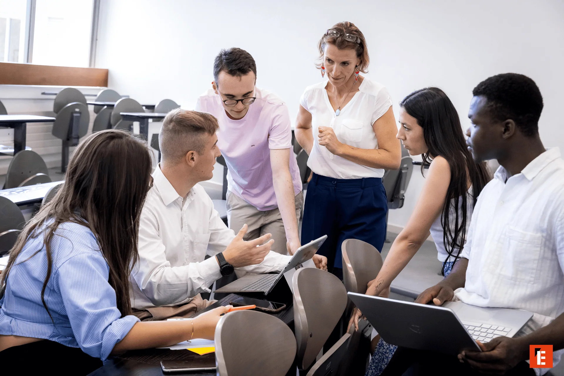Groupe détudiants en travail collaboratif autour dune tablette en salle de classe moderne.