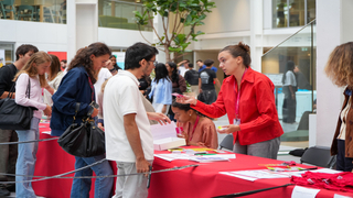 Stand dinscription dans latrium avec bénévoles, file dattente, brochures et T-shirts.