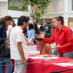 Stand dinscription dans latrium avec bénévoles, file dattente, brochures et T-shirts.