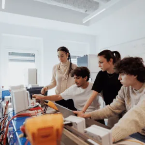 Labo électronique : groupe détudiants travaillant sur postes, multimètres et câbles.