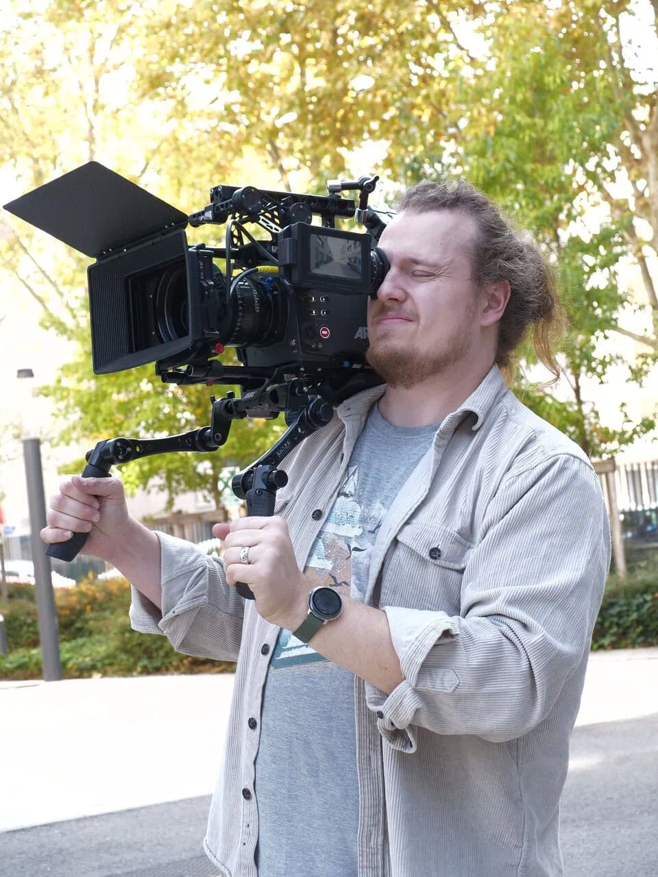Opérateur caméra épaule professionnel en tournage extérieur, caméra cinéma avec matte box et moniteur.