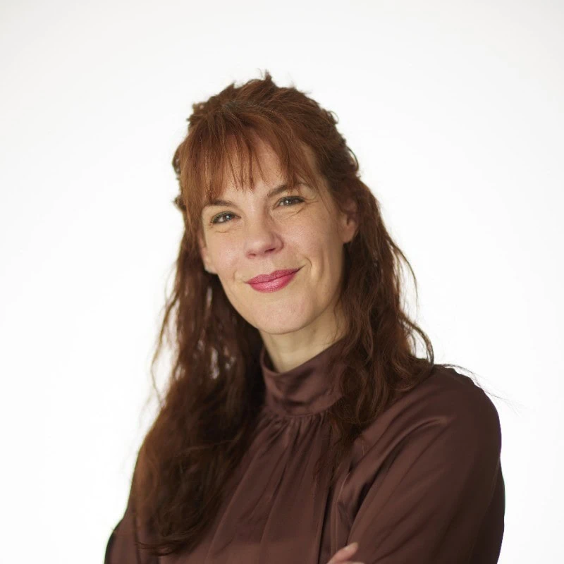 Portrait studio femme souriante cheveux roux, blouse marron satinée, photo professionnelle.