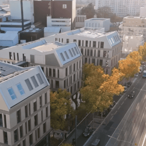 Vue aérienne dun quartier moderne avec immeubles, tramway, arbres dautomne et façades lumineuses.
