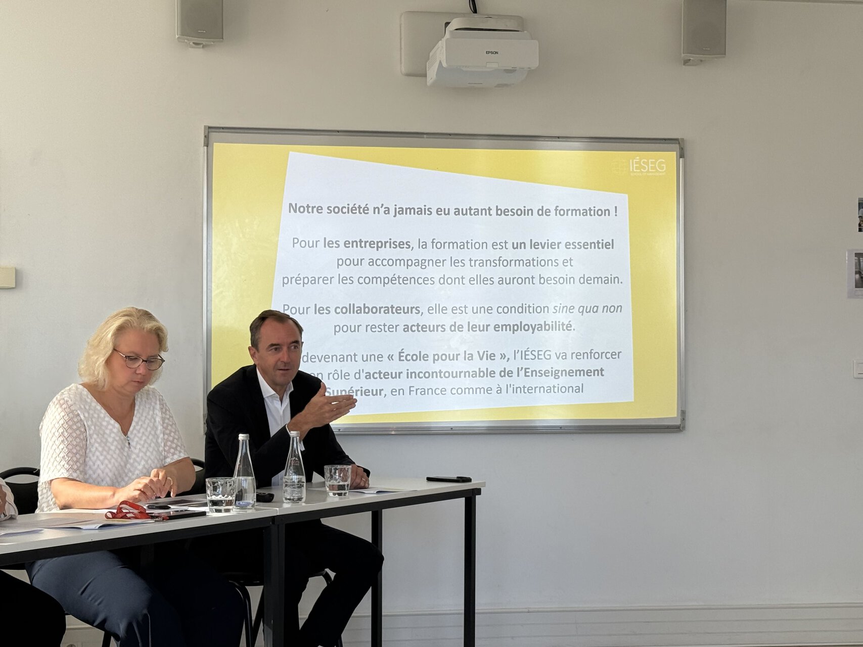 Présentation projetée en salle de réunion IÉSEG, deux intervenants discutent.