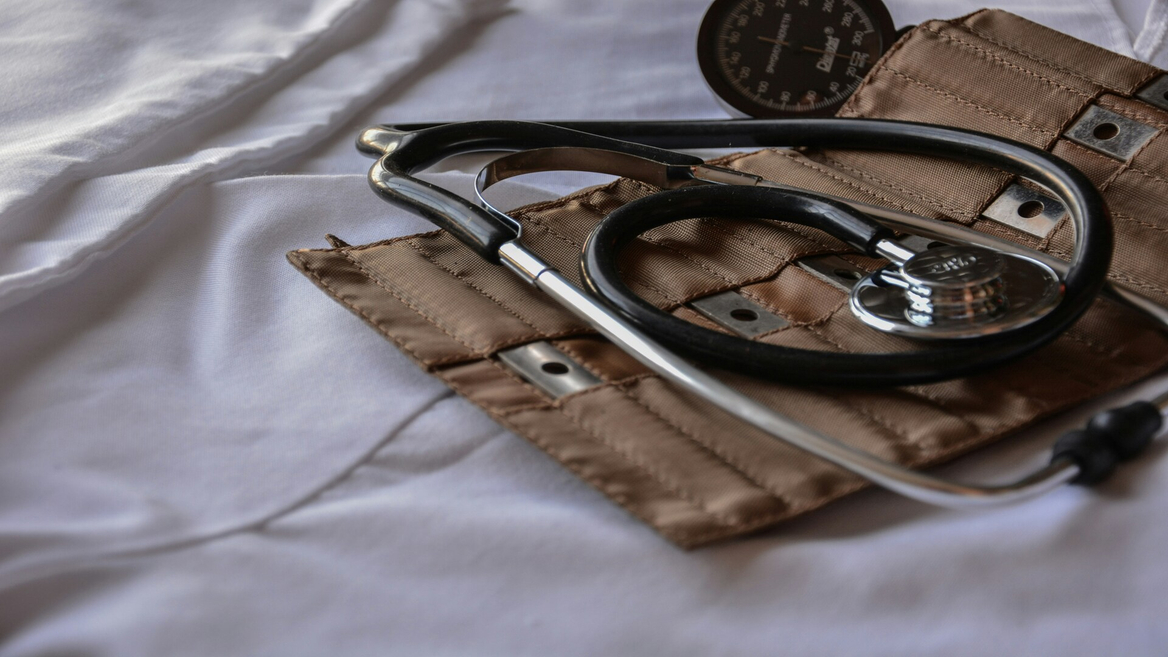 Stéthoscope et tensiomètre sur tissu blanc, instruments médicaux de clinique et brassard.