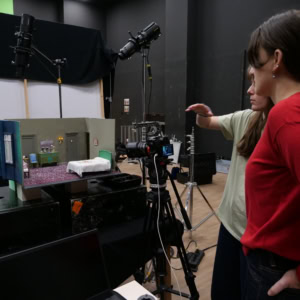 Studio photo avec diorama miniature, caméra, éclairage professionnel et équipe en action.