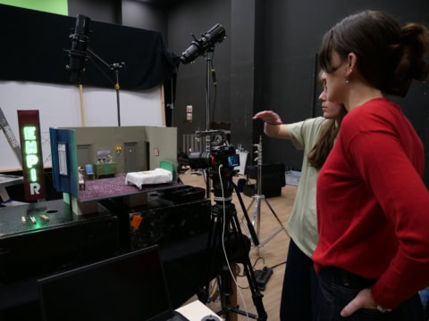 Studio photo avec diorama miniature, caméra, éclairage professionnel et équipe en action.