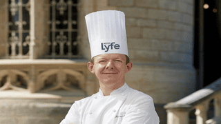 Chef professionnel en extérieur, portrait institut avec toque Lyfe et veste blanche.