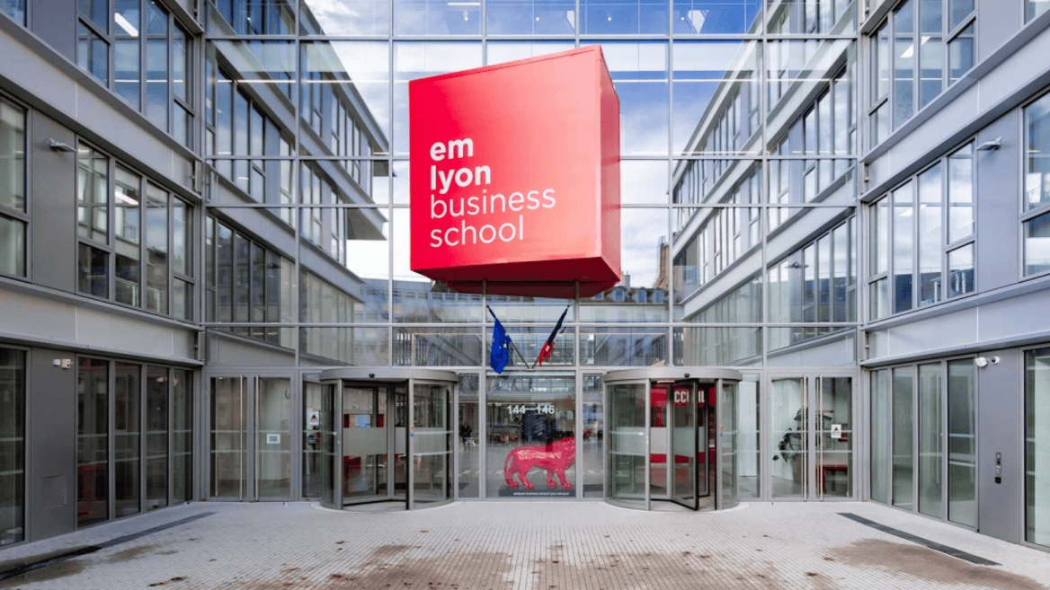 Entrée em lyon business school : cube rouge suspendu, façade vitrée et portes tournantes.