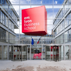 Entrée em lyon business school : cube rouge suspendu, façade vitrée et portes tournantes.