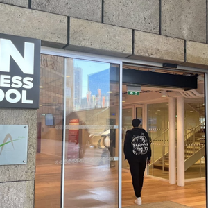 Entrée vitrée ICN Business School, façade en pierre, étudiant avec sac à dos.