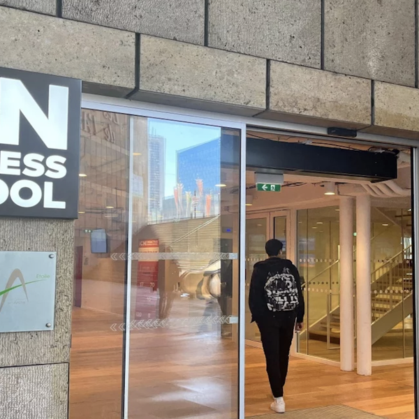 Entrée vitrée ICN Business School, façade en pierre, étudiant avec sac à dos.