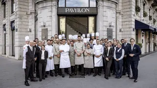 Équipe de restaurant professionnelle devant le Pavillon, chefs en toques et personnel en uniforme.