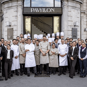 Équipe de restaurant professionnelle devant le Pavillon, chefs en toques et personnel en uniforme.