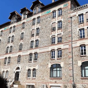 Façade en pierre dimmeuble historique au soleil, fenêtres et stores rayés.