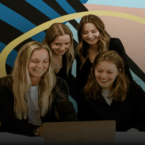 Groupe détudiants souriants autour dun ordinateur portable, collaboration et brainstorming en équipe.