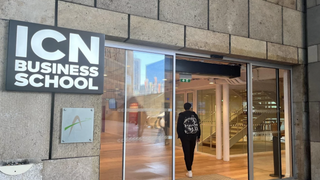 Entrée vitrée ICN Business School, façade en pierre, étudiant avec sac à dos.