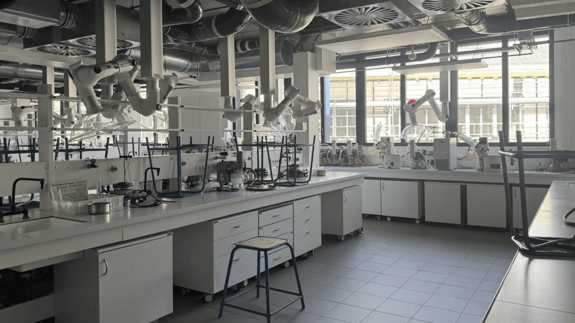 Laboratoire moderne avec bancs de travail, hottes articulées, verrerie et équipements de chimie.