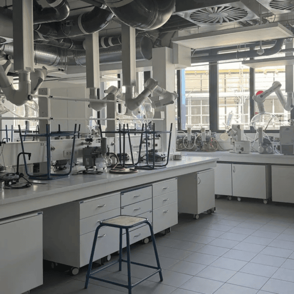 Laboratoire moderne avec bancs de travail, hottes articulées, verrerie et équipements de chimie.