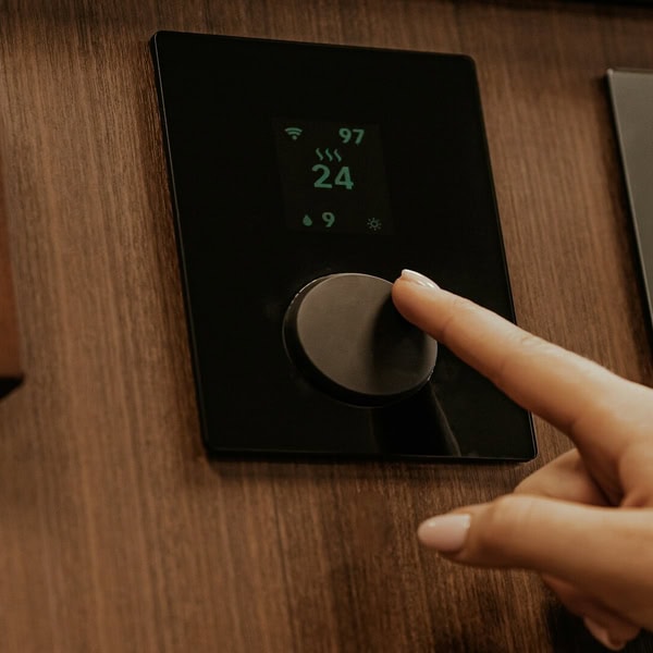 Thermostat mural domotique encastré dans bois, molette tactile et affichage 24°C.
