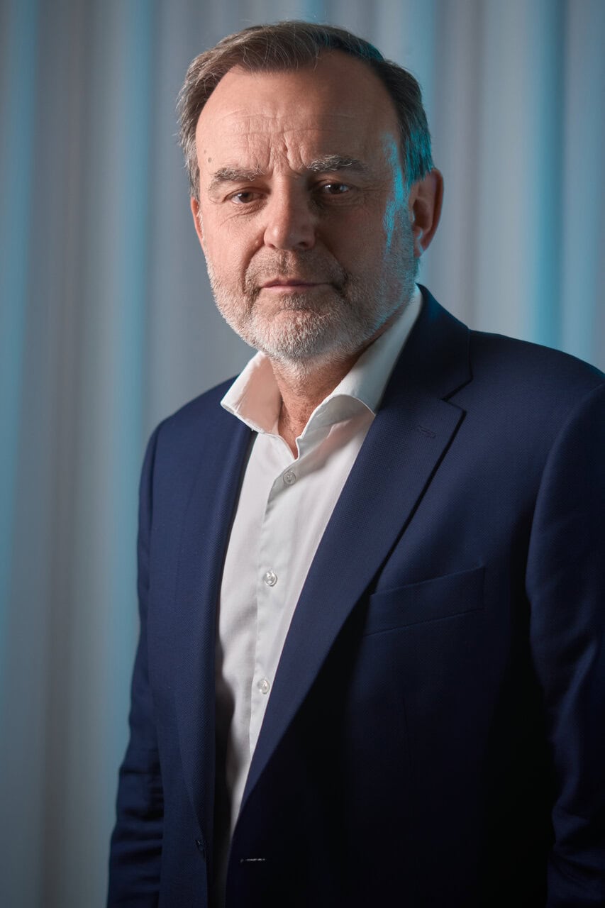 Portrait studio dhomme mature professionnel en costume, barbe grise, regard direct.
