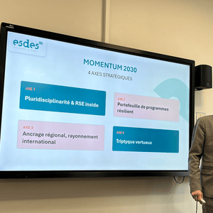 Présentation Momentum 2030 esdes Business School : intervenant devant écran affichant 4 axes stratégiques.