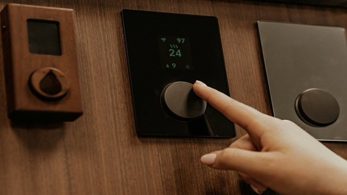 Thermostat mural domotique encastré dans bois, molette tactile et affichage 24°C.